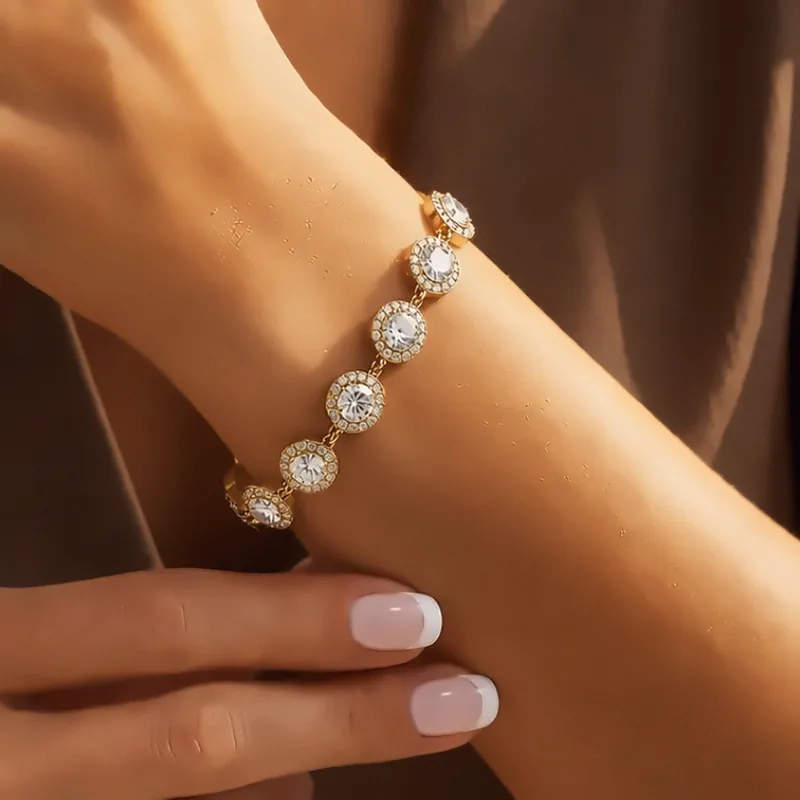 Goldenes Armband mit runden, gefassten Steinen am Handgelenk.
